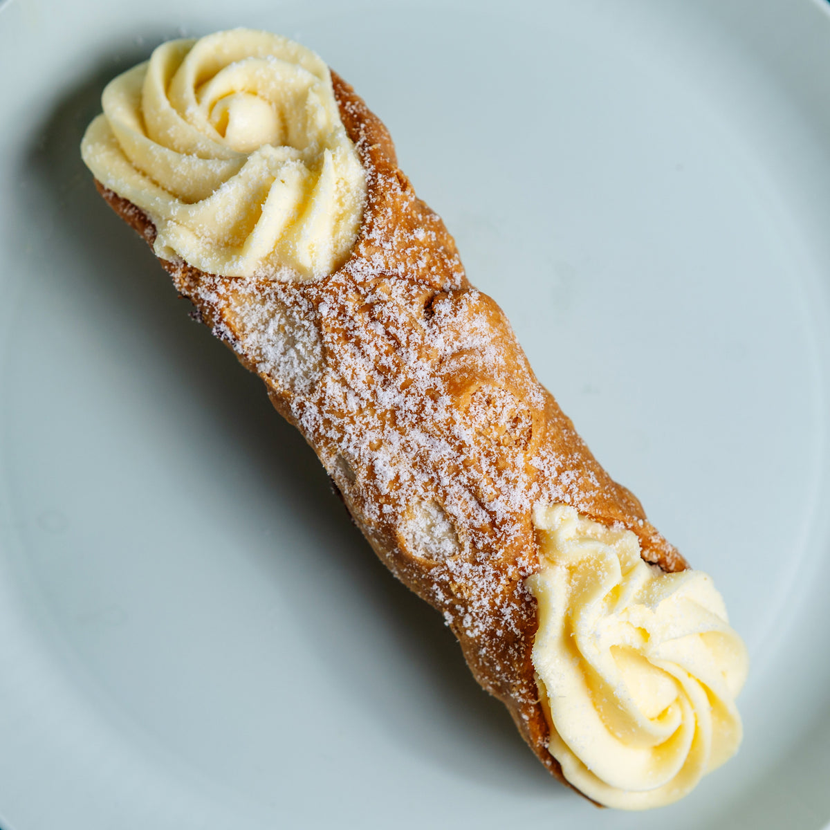 Crisp Italian cannolo filled with vanilla custard cream and dusted with icing sugar, Milano Cakes Wollongong