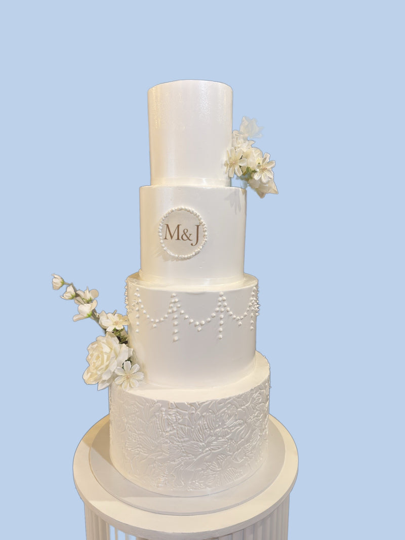 Four-tier monogram wedding cake with sugar flowers